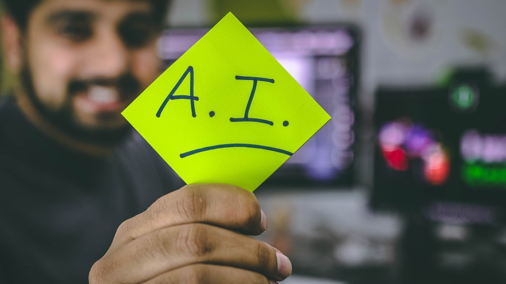 A man holding a post-it note with AI on it
